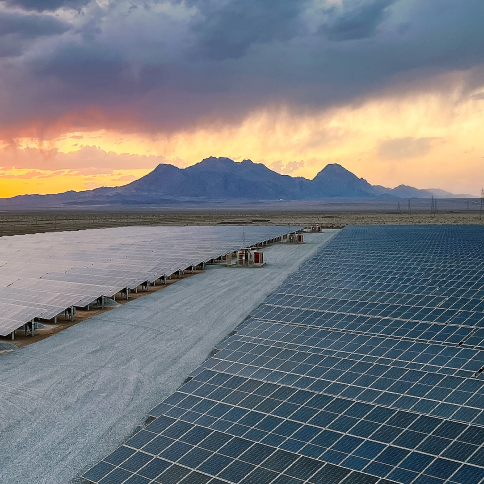 Planta de generación solar, en el atardecer con una montaña de fondo.