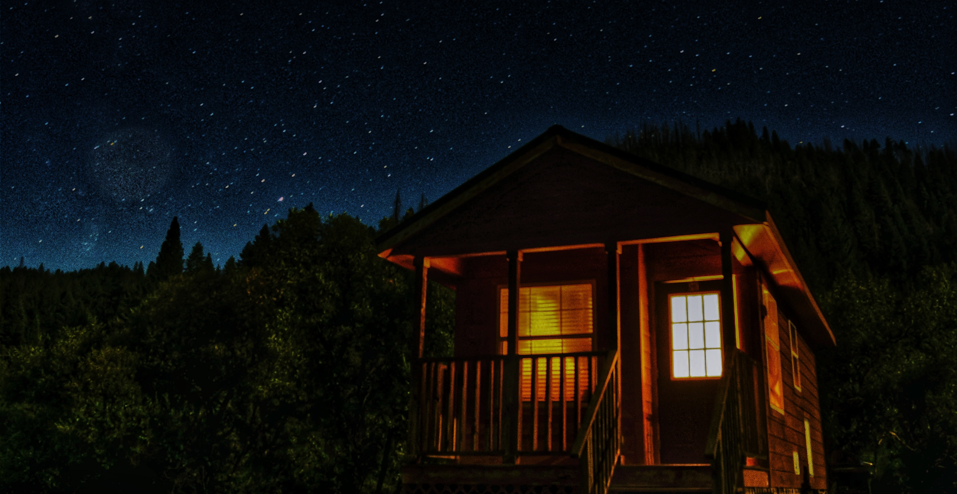 Imagen de fondo de una casa iluminada en la noche, con el cielo estrellado.